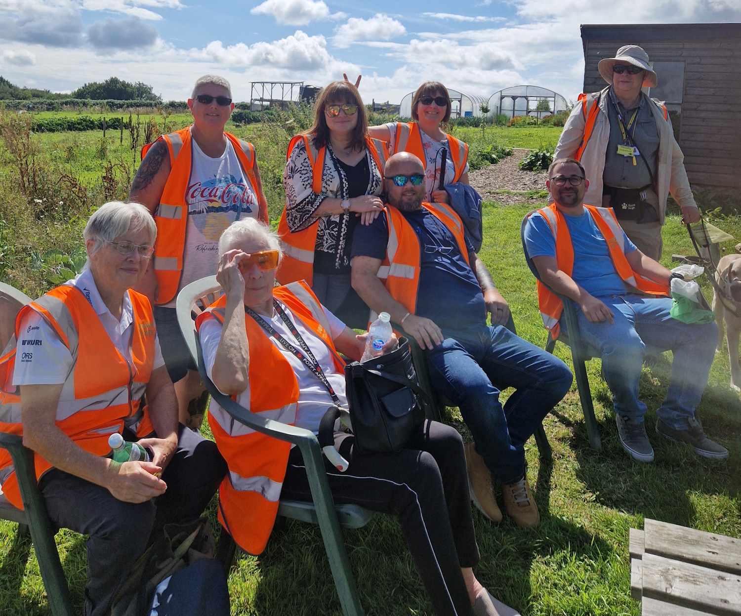 A group of members at 'Down to Zero’ in Mwyndy. Some are sitting down, some are standing. They are all wearing orange high-vis vests and are smiling to camera.
