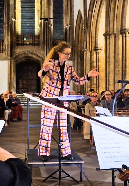 Picture of Georgia conducting the Orchestra in front of an audience at Llandaff Catherdral.