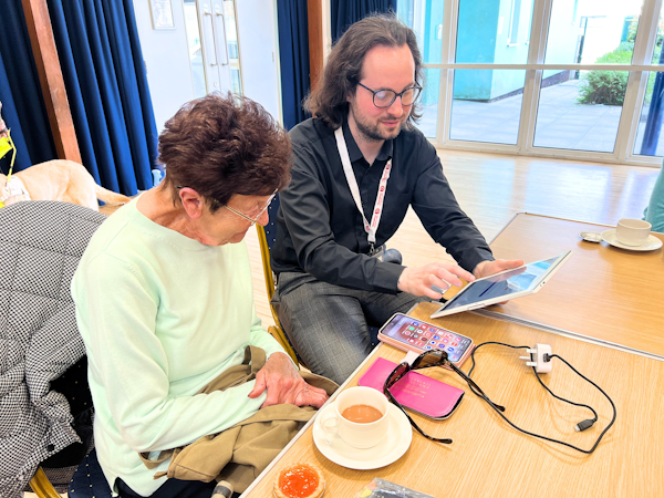 Picture of a member of the Age Connects team demonstrating technology to a service user.